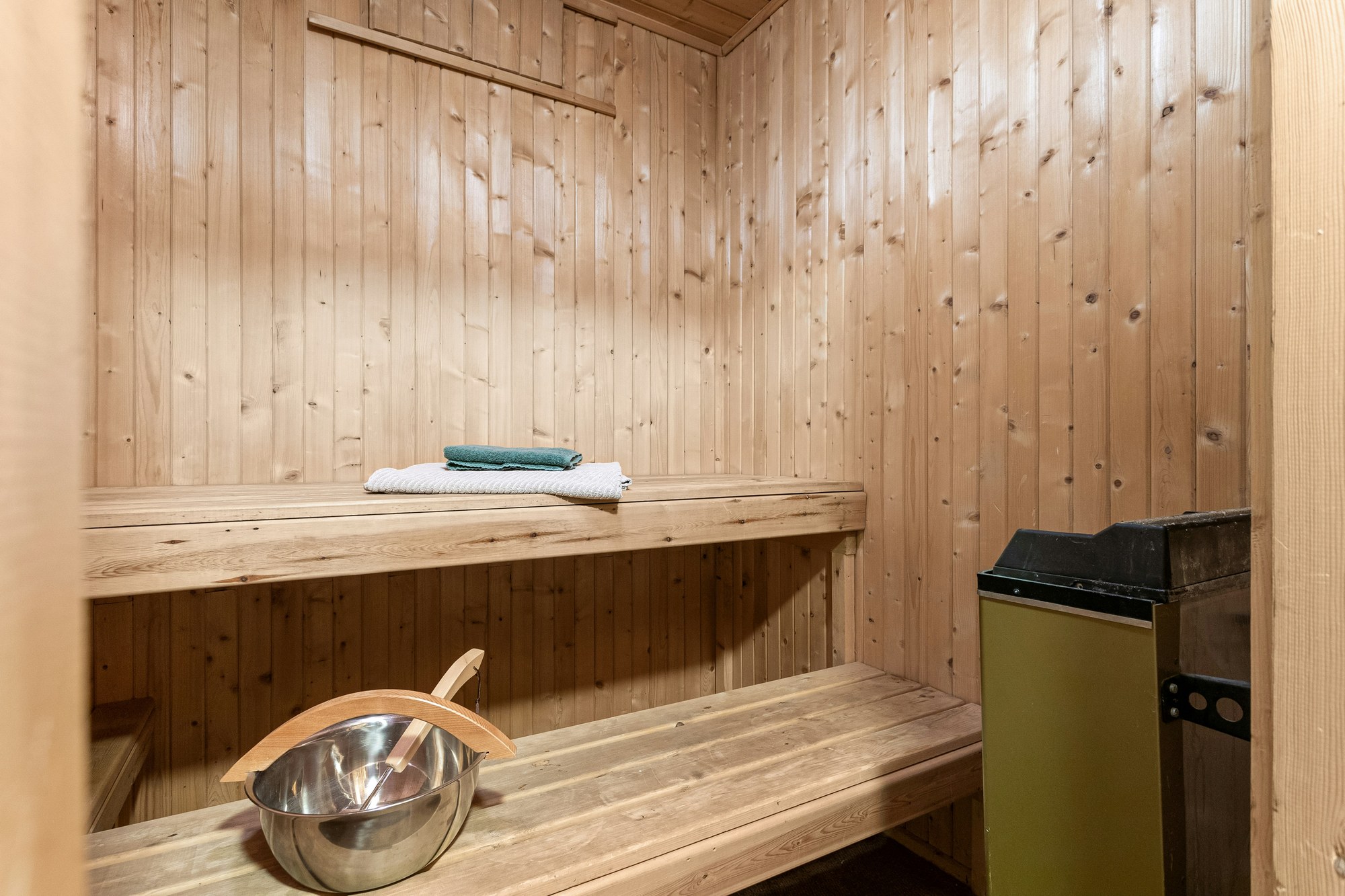 Compact pine sauna with a small heater, bench and bucket in a Sonoma home